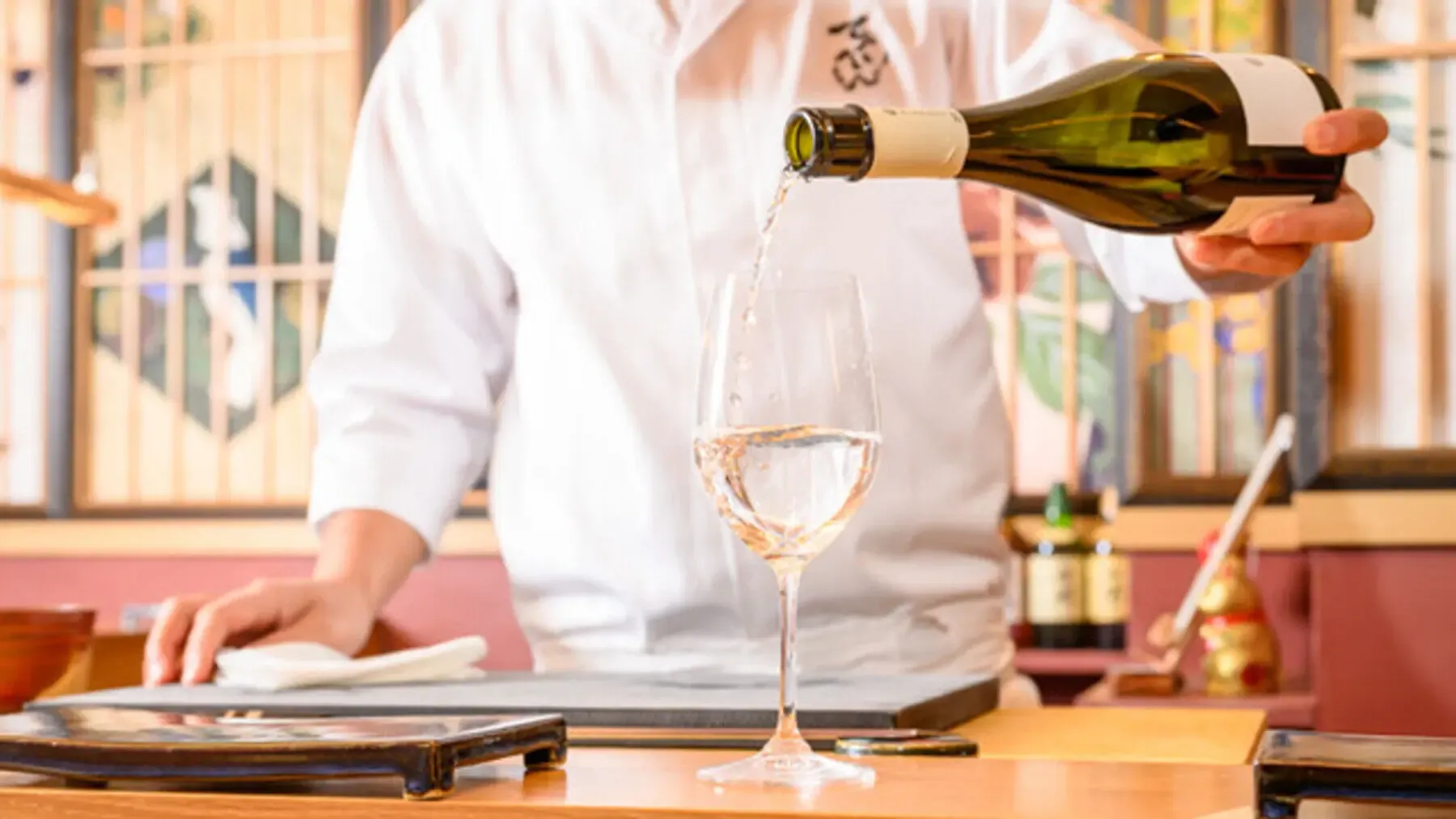 鮨てっぺんのカウンターで飲み物を注ぐ様子